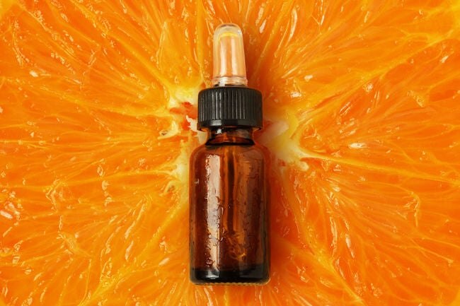 Taze portakal dilimi üzerinde C vitamini yüz serumu şişesi